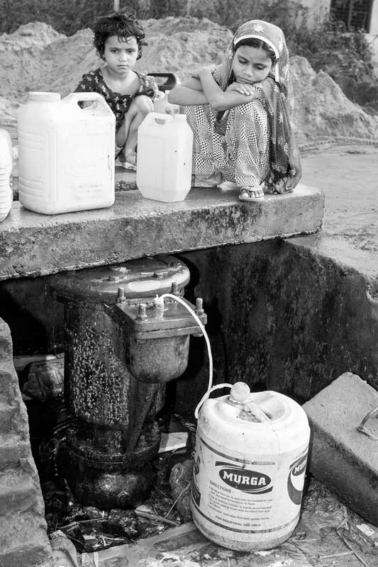 Human Right to Water in Delhi - Children residing in an unauthorized colony in Delhi procuring water from a valve leakage at a water main